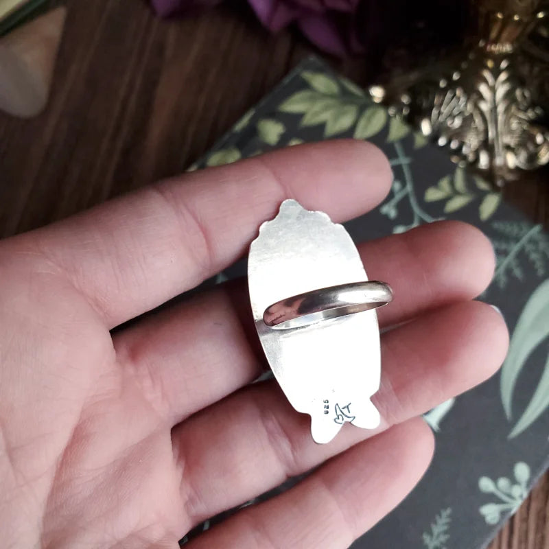 a person holding a silver ring with a heart on it