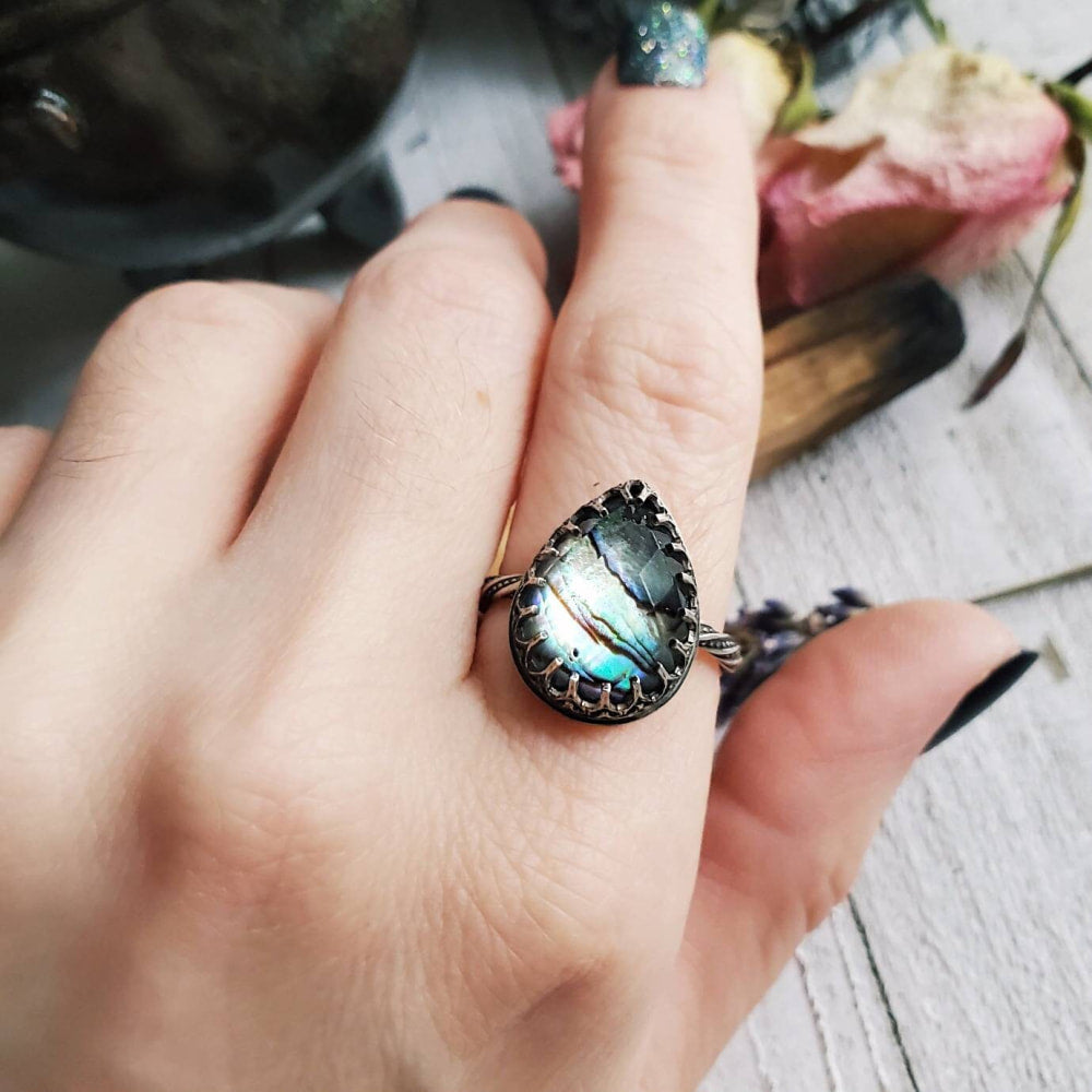 someone is holding a ring with a blue stone in it