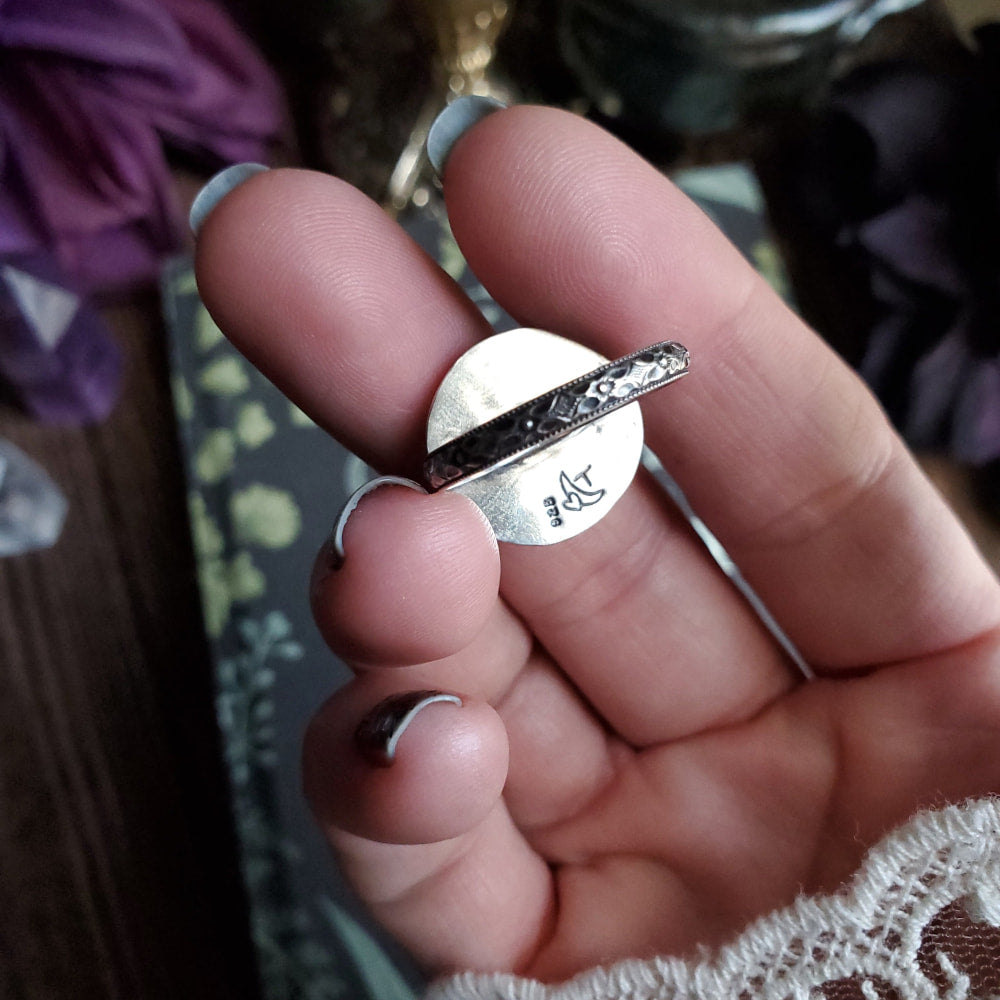 a person holding a silver ring with a small bird on it
