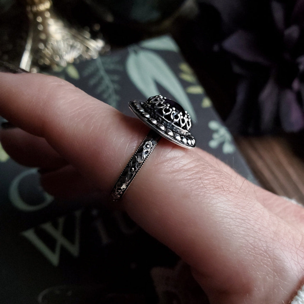 a woman’s hand holding a ring with a skull on it