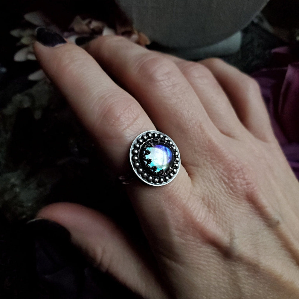 a person’s hand holding a ring with a blue stone