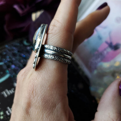 a person holding a silver ring with a flower design