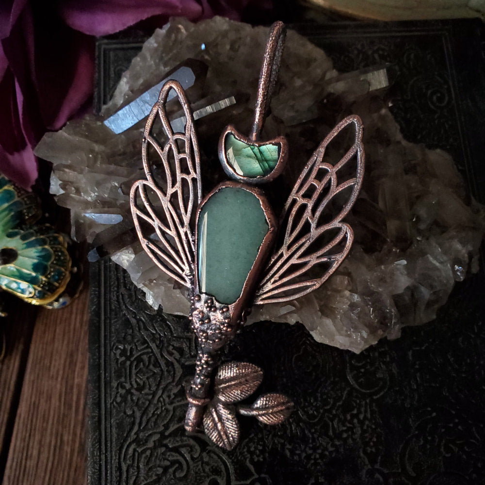 a green stone pendant with a copper dragon on it