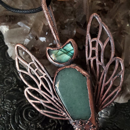a green stone pendant with copper accents