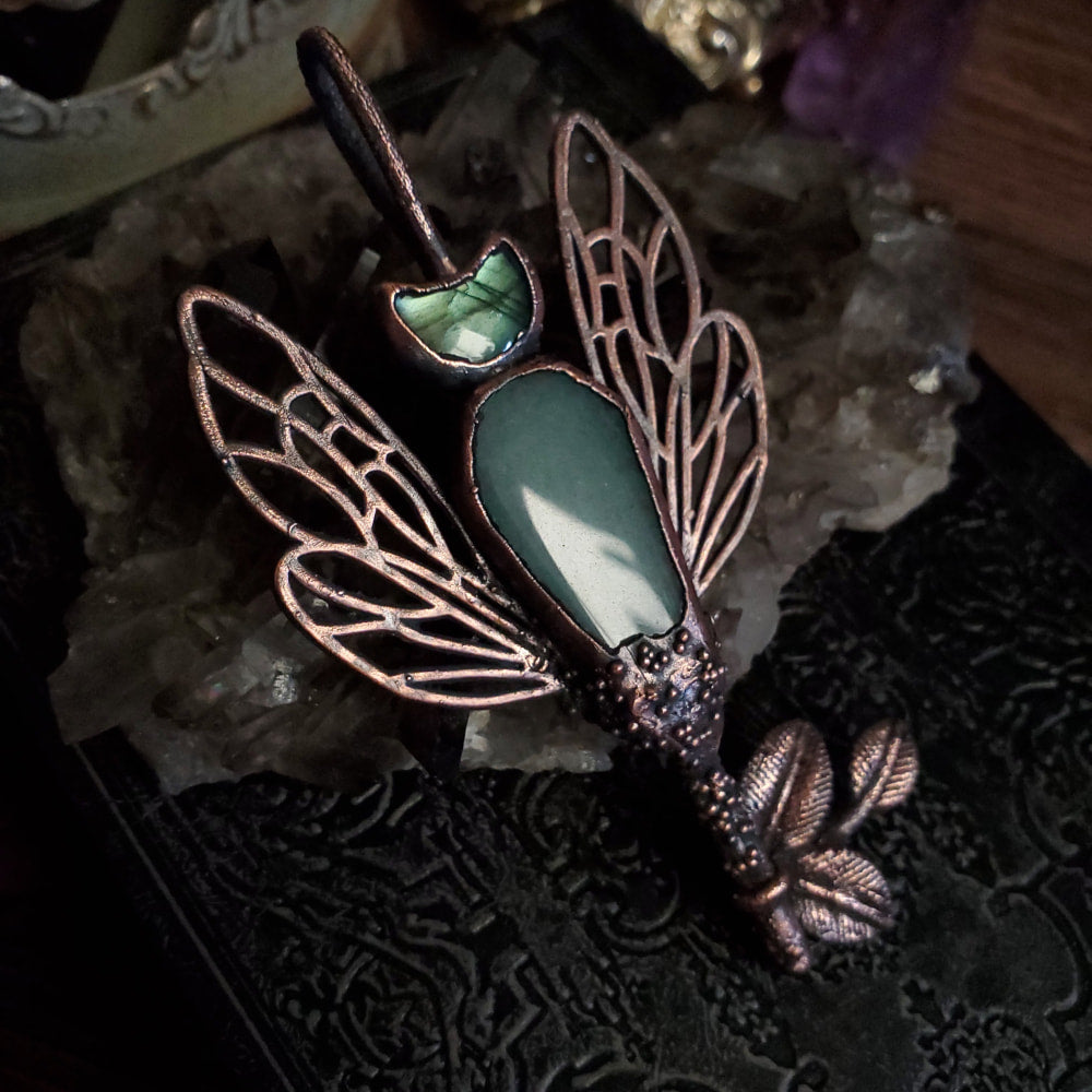there is a green dragonfly brooch on a book
