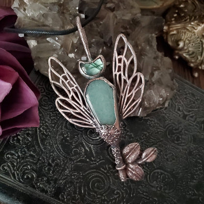 a green stone pendant with a butterfly on it