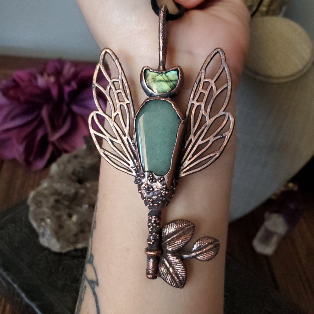 a woman holding a green stone and a butterfly