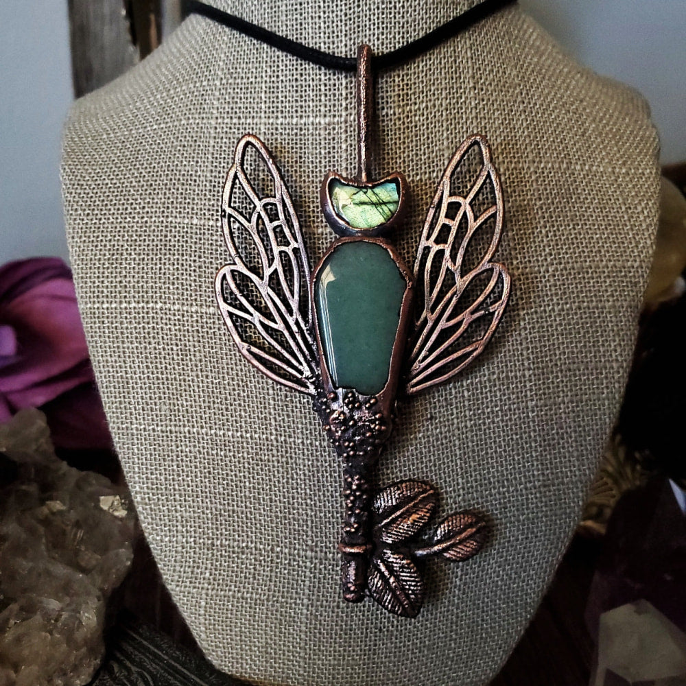 a necklace with a green stone and a copper dragon