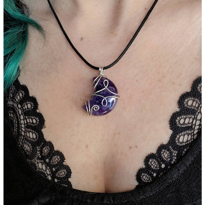 a woman wearing a necklace with a purple stone