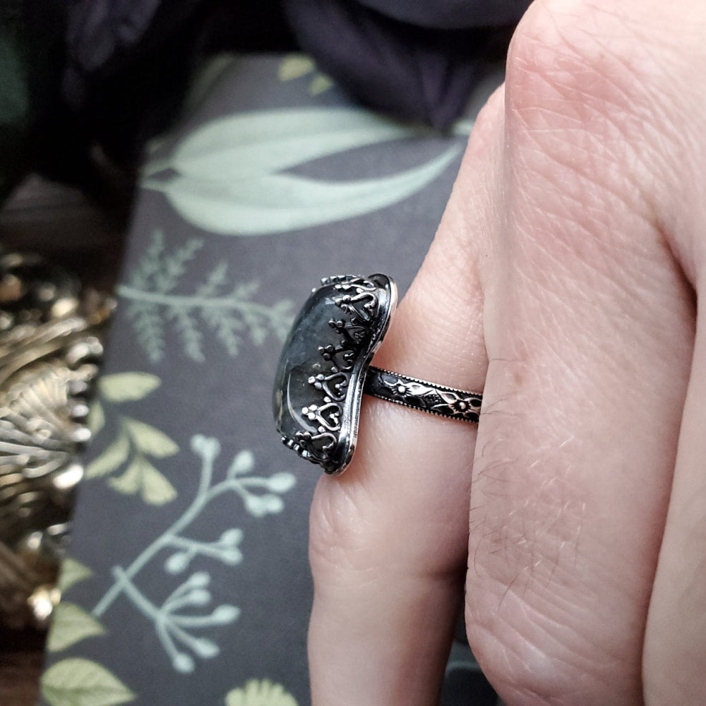 a person holding a ring with a black stone