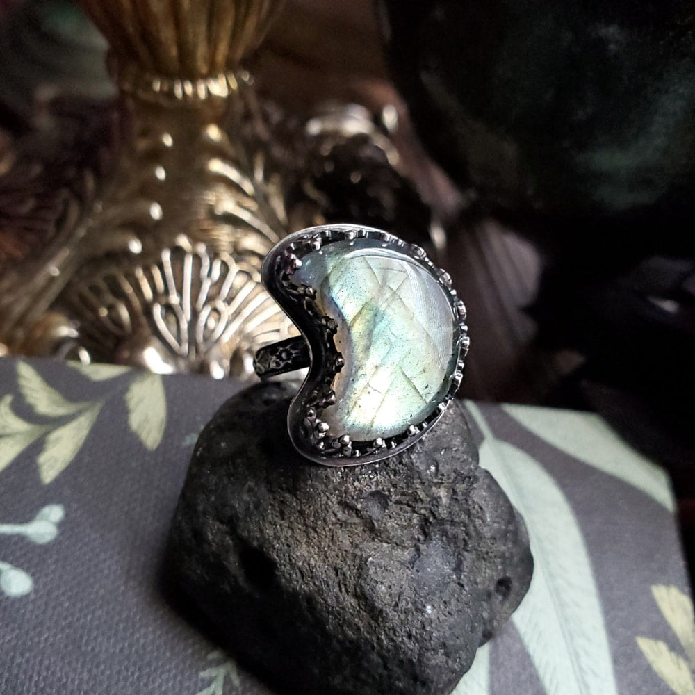 there is a ring with a labradorite stone on a rock