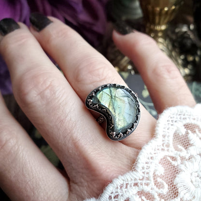 a woman’s hand holding a ring with a green stone