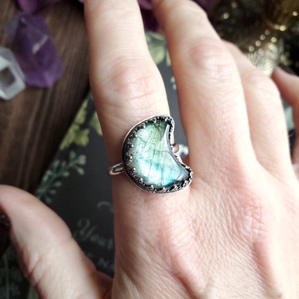 someone is holding a ring with a green and blue stone