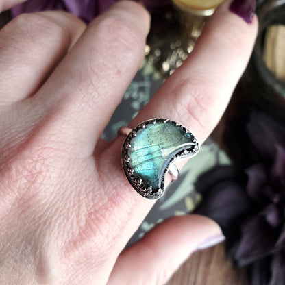 a person’s hand holding a ring with a blue stone