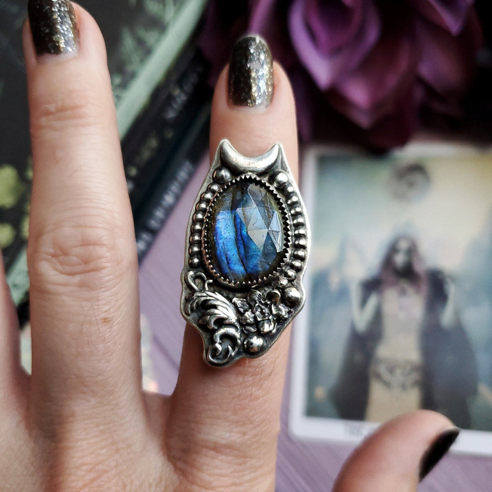 a woman’s hand holding a ring with a blue stone