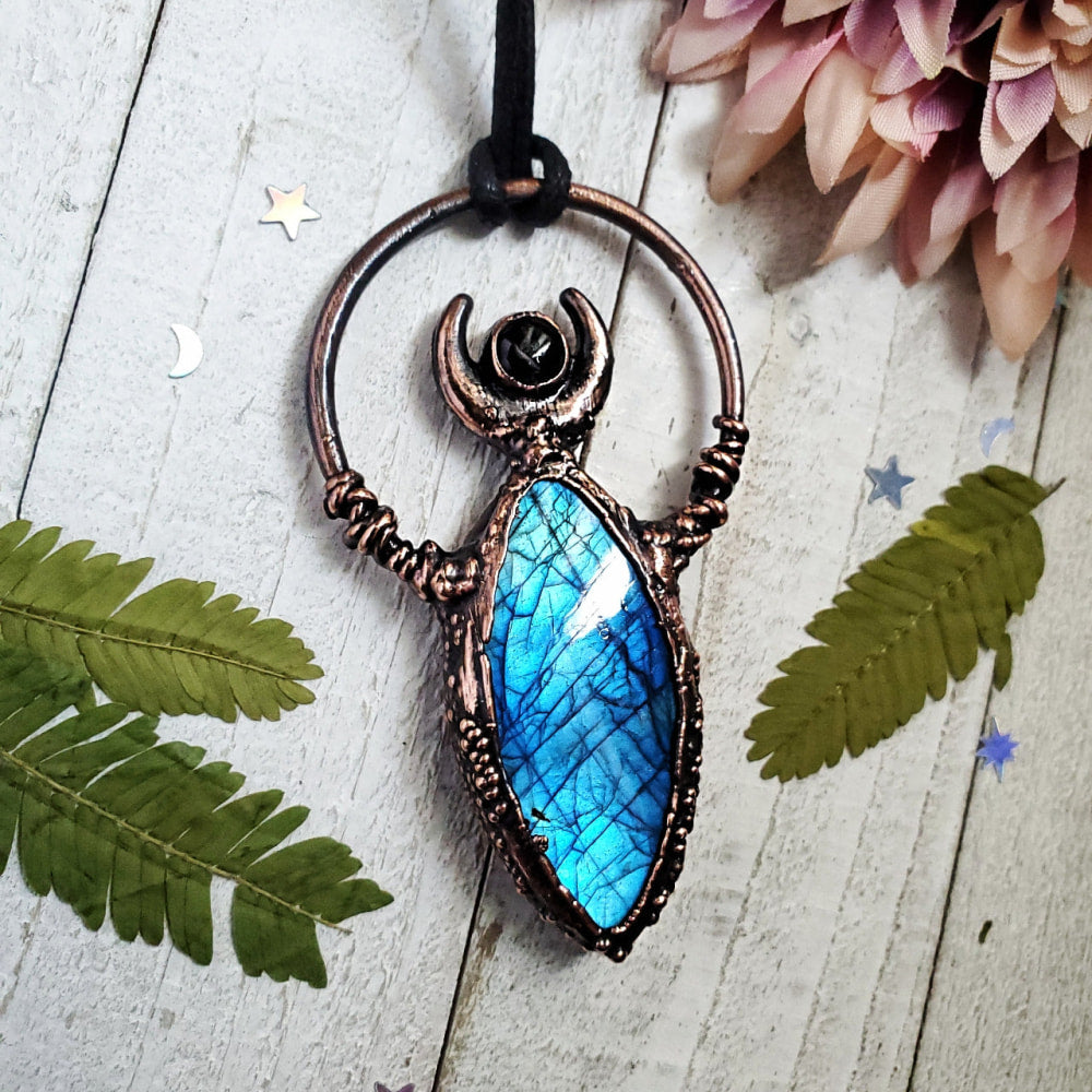 a blue stone pendant hangs on a black cord