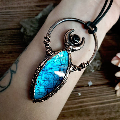 a woman’s hand holding a blue stone pendant