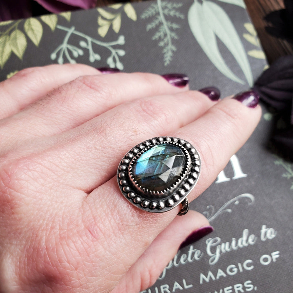 a woman’s hand holding a ring with a blue stone