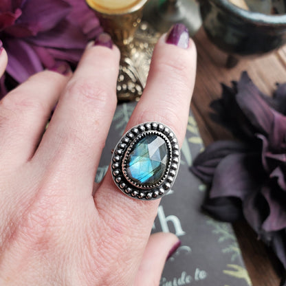 a woman’s hand holding a ring with a blue stone