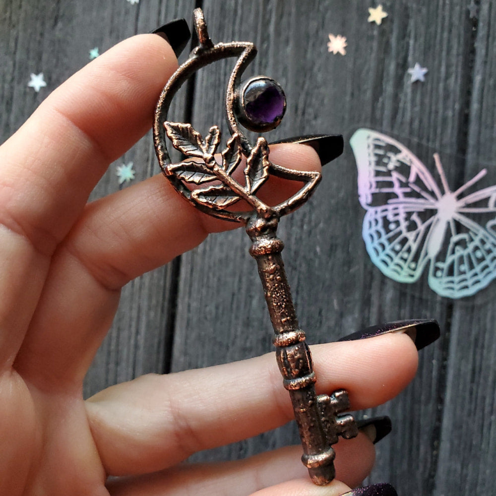 a person holding a small key with a purple stone