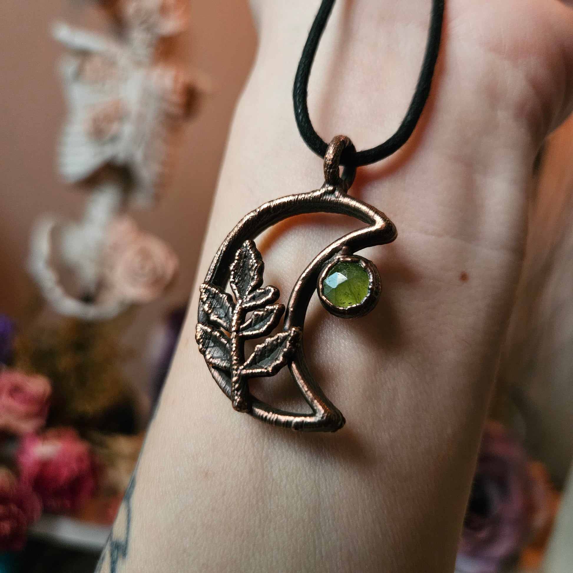 a woman’s hand holding a green stone pendant