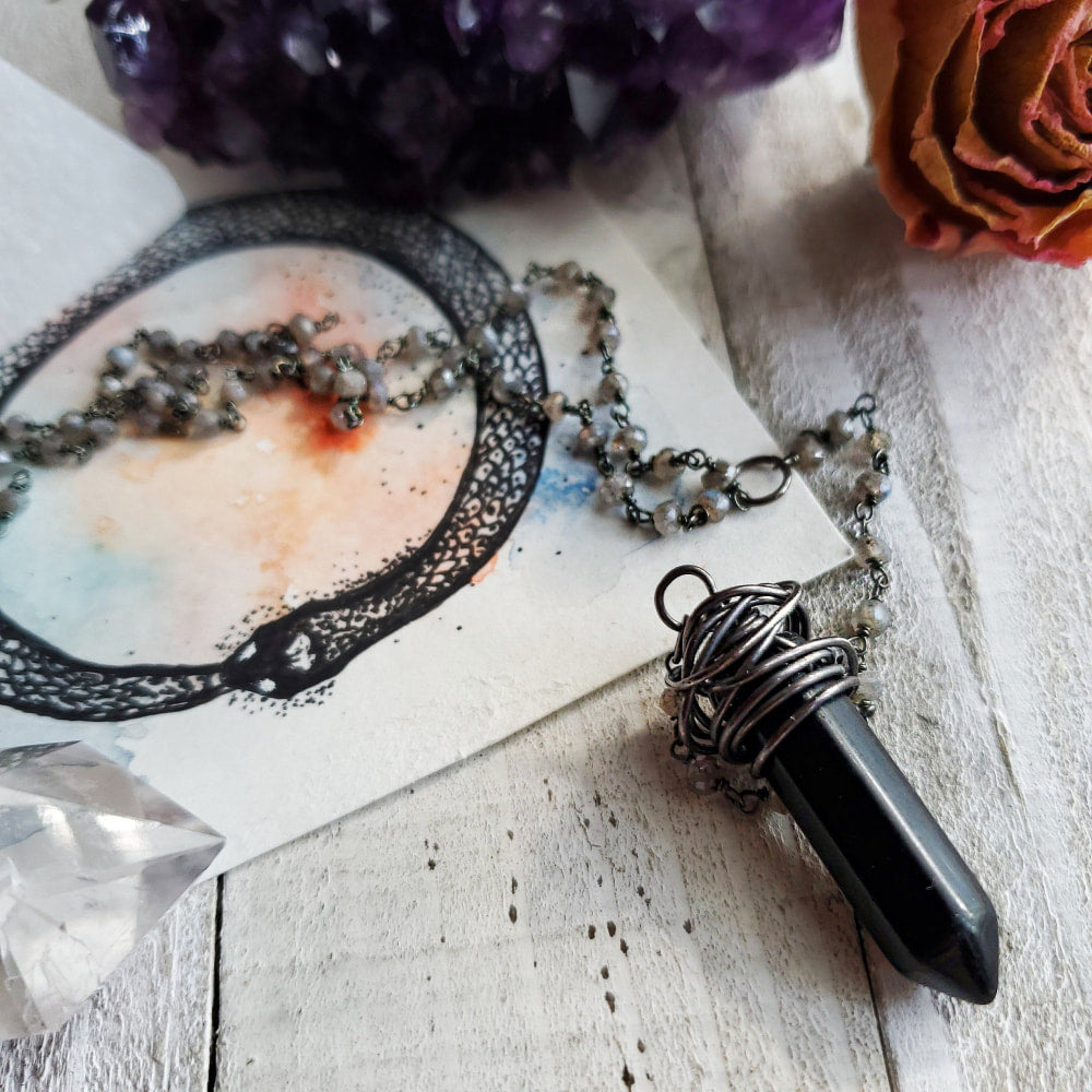 a necklace with a black stone pendant and a flower