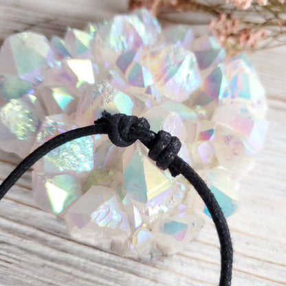 a white crystal stone on a black cord bracelet