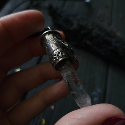 Ornate metal vial or container holding a clear liquid substance.