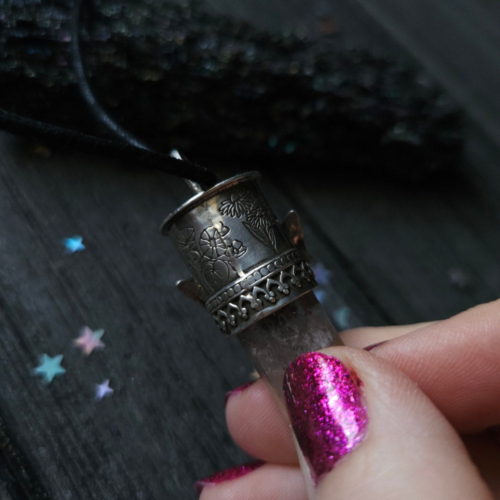 Ornate silver thimble held by fingers with bright pink glittery nail polish.