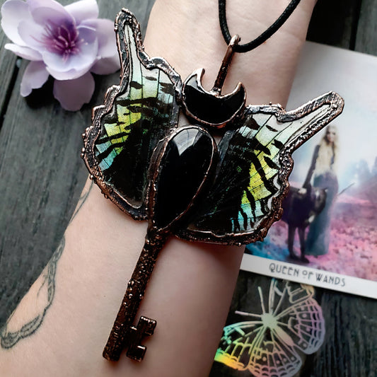a butterfly shaped necklace with a key on it