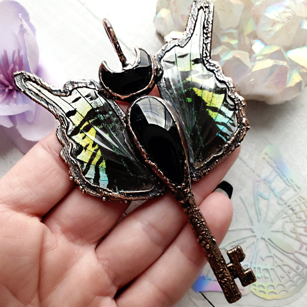 someone holding a butterfly shaped brooch with a key in it